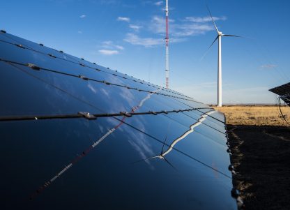 A solar panel next to a wind turbine