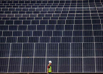 A man walking in front of a large solar installation