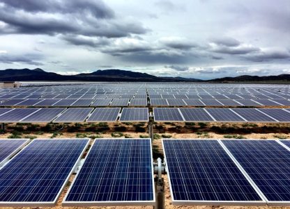 A solar farm in Utah, with mountains and clouds in the background