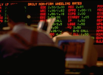 A trader sits against a wall of trading information
